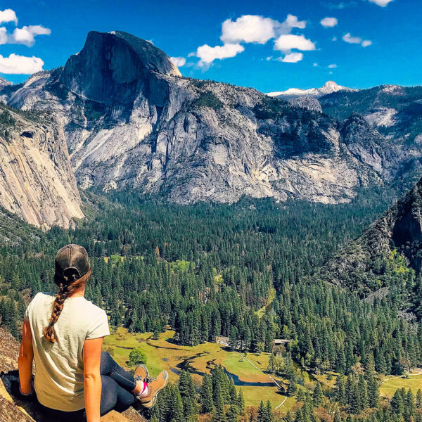 A woman sits on a rock overlooking Yosemite Valley during a small group tour in California.